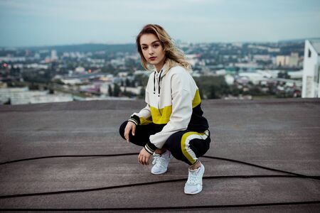 Stylish female sitting on haunches on roofの写真素材