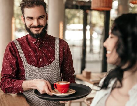 Cheerful waiter giving order to client in cafeの写真素材