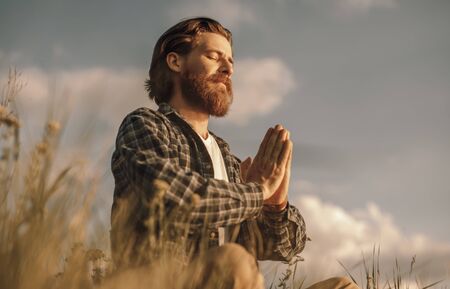 Adult man meditating in summer fieldの写真素材
