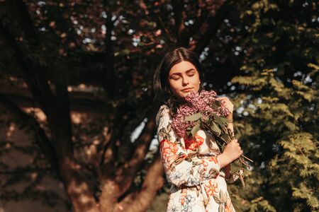 Young woman smelling flowers in parkの写真素材