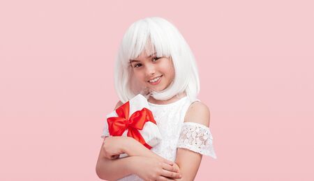 Cheerful teenager in white wig hugging presentの写真素材