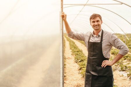 Happy male farmer standing in greenhouseの写真素材