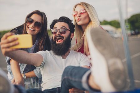Bearded man taking selfie with women during shoppingの写真素材