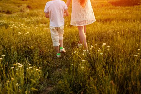 Crop brother and sister walking in meadowの写真素材