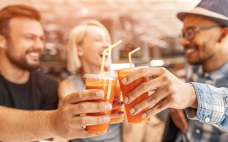 Cheerful friends toasting with carrot juice