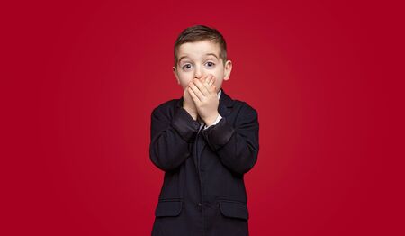 Shocked schoolboy covering mouthの写真素材