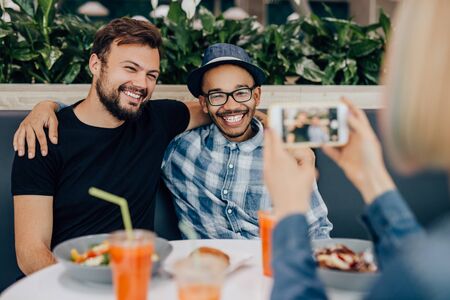 Crop woman taking photo of male friends