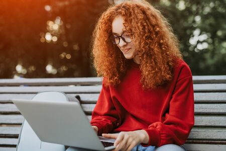 Young woman sitting on bench and using laptopの写真素材