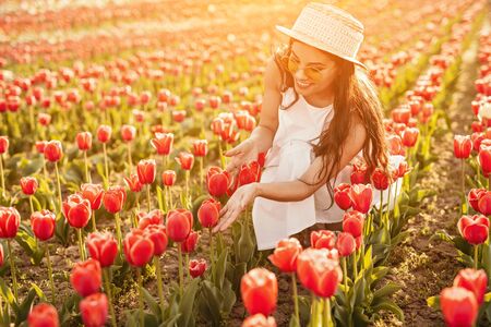 Happy female traveler enjoying tulips in fieldの写真素材