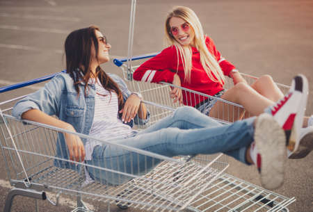 Happy friends in shopping trolleys talking with each otherの写真素材