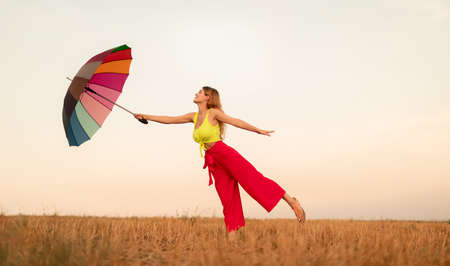 Carefree lady dancing with umbrella in eveningの写真素材