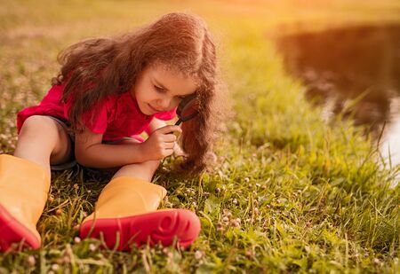 Little girl with magnifier exploring natureの写真素材