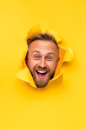 Excited man tearing paper with headの写真素材