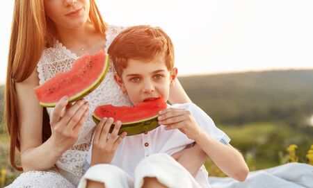 Siblings eating watermelon in countrysideの写真素材