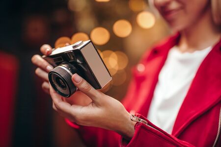 Closeup of female tourist with retro photo camera against blurred lights outdoorsの写真素材