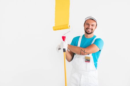 Friendly worker painting wall with yellow paintの写真素材