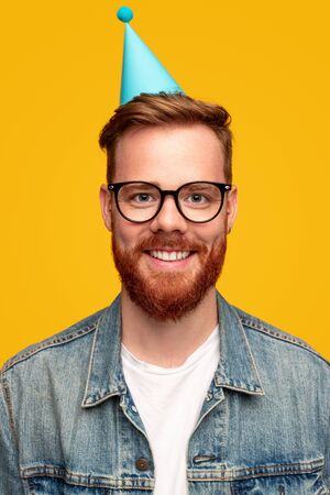 Cheerful bearded man in birthday capの写真素材