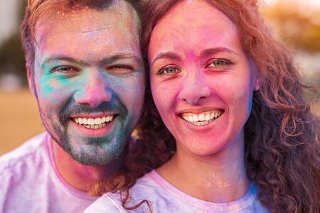 Cheerful friends looking at camera during paint partyの写真素材