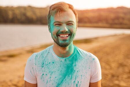 Cheerful man during paint party on beachの写真素材