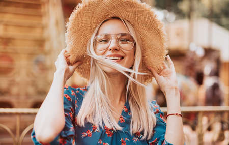 Happy young woman in hat standing on funfairの写真素材