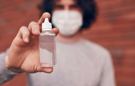 Blurred man showing bottle of sanitizerの写真素材
