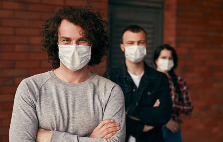 Man in mask standing near friendsの写真素材