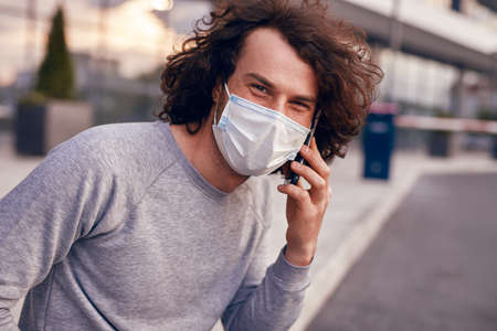 Man in mask speaking on smartphone on streetの写真素材