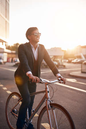 Happy businessman riding bike in cityの写真素材