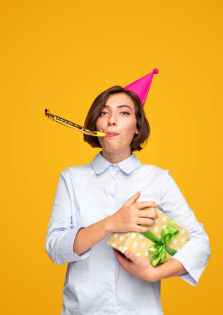 Female blowing party horn during birthday celebrationの写真素材