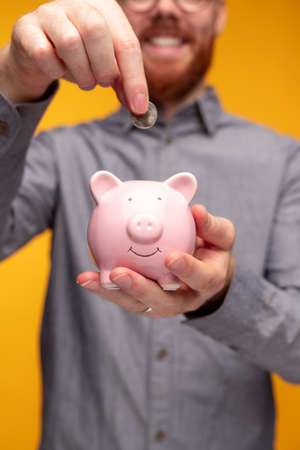 Crop man saving money in piggy bank