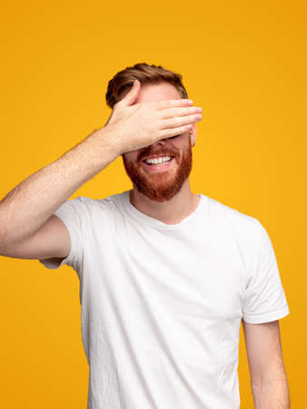 Cheerful bearded man covering eyesの写真素材