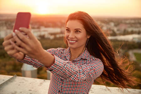 Happy ethnic woman taking selfie on roof