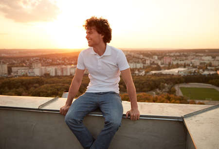 Happy man chilling on roof during sunsetの写真素材