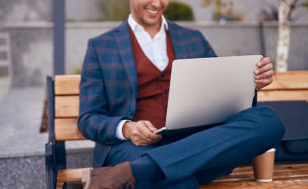 Crop businessman using laptop on benchの写真素材