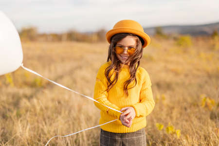 Cheerful girl with balloon in meadowの写真素材