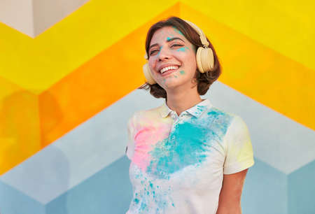 Delighted female hipster with colorful face listening to music