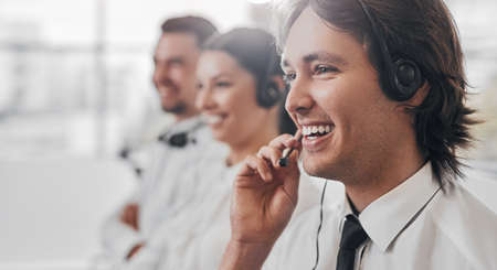 Cheerful male operator speaking with customerの写真素材