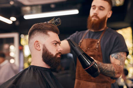Blurred barber drying hair of client