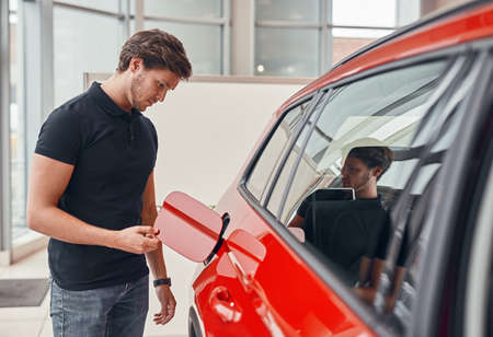 Serious man checking fuel tank of carの写真素材