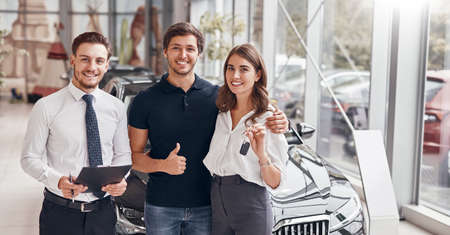 Happy clients and manager in car dealership