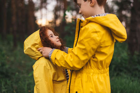 Boy putting hood on sister in forestの写真素材