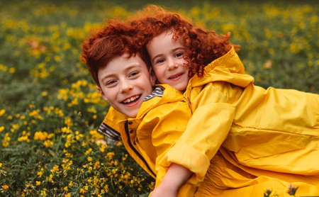 Ginger siblings hugging on blooming lawnの写真素材