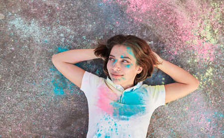 Glad woman resting on ground during paint partyの写真素材