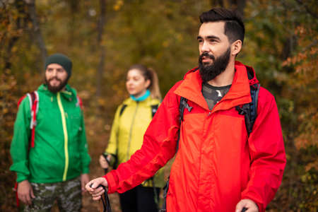 Young backpackers in warm jackets exploring autumn forestの写真素材