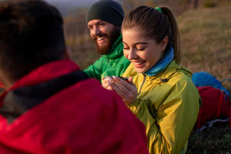 Happy hikers enjoying hot tea during trekking in natureの写真素材