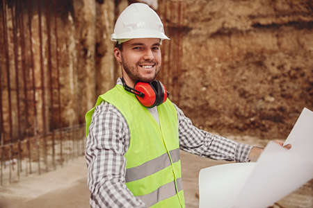 Happy engineer reading draft on construction site