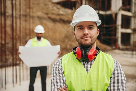 Confident young engineer standing on construction site