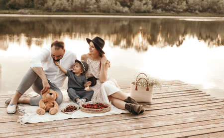Happy family having picnic on lake pierの写真素材