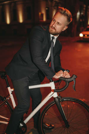 Bearded businessman riding bicycle at nightの写真素材