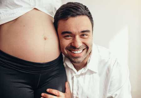 Happy man hugging pregnant womanの写真素材
